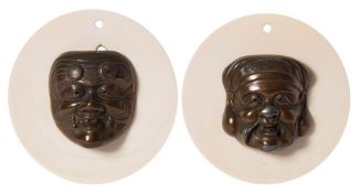 A pair of Japanese bronze Noh masks: mounted on circular ivory mounts, each mask 5cm.
