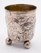 A Continental silver mug: with embossed floral decoration, raised on three ball feet, split to rim,