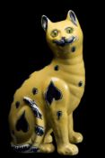 A Mosanic pottery cat: modelled seated and painted with blue circle and heart motifs on a yellow