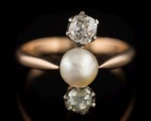 A 'pearl' and diamond three-stone ring: the single 'pearl' approximately 5mm diameter,