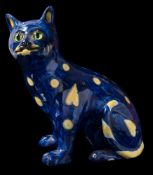 A pottery cat, probably Mosanic: modelled in seated posture with inset green glass eyes,