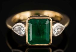 An 18ct gold, emerald and diamond ring: the rectangular emerald approximately 9.2mm long x 8.