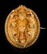 A mid-Victorian gold oval brooch locket: with a hinged front panel of textured foliate filigree