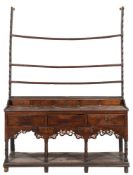 An 18th Century oak dresser:, the shelved superstructure with a shaped apron canopy,