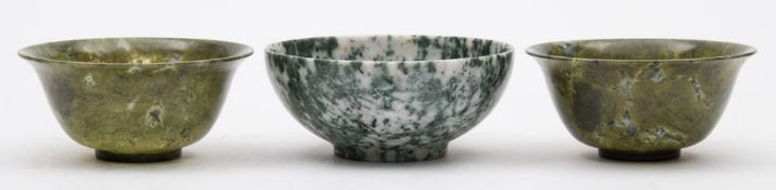 Two Chinese green jadeite bowls: of plain circular form raised on a circular foot, each 10cm.