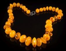 A large amber bead, single-string necklace: with individually knotted, graduated round beads,