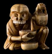 A 20th century Japanese carved ivory netsuke: of a skeleton pouring tea from a teapot into a bowl,