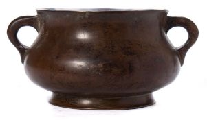 A Chinese bronze censer: of squat circular form, with loop handles to the side, on a circular foot,