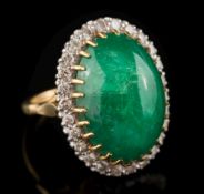 A cabochon emerald and diamond oval cluster ring: the oval cabochon emerald approximately 22mm long