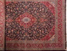 A Kashan carpet:, the indigo cartouche field with a central red cartouche pole medallion,
