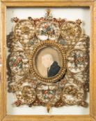 An early 19th century picture frame: the centre with a miniature of a gentleman in frock coat,