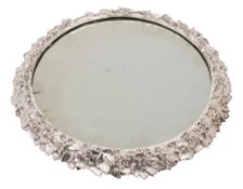 A silver plated table centrepiece: of circular form: the mirror plate enclosed by a vine leaf and