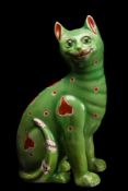 A Mosanic pottery cat: modelled seated and painted with red circle and heart motifs on a green