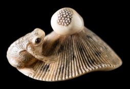 A Japanese carved ivory netsuke in the style of Garaku: carved as a toad seated on an upturned