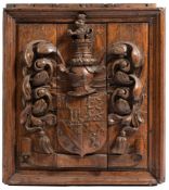 A carved oak coat of arms plaque: the quartered shield surmounted by a knight's helmet,