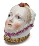 A Chelsea bonbonniere: modelled as a lady's head wearing a pink ribbon trimmed mob-cap with feather