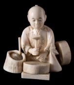A Japanese ivory okimono of a seated merchant: in front of a mill stone with hammer in hand,