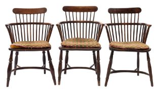 A harlequin set of five early 19th Century yew-wood, elm and beech comb back Windsor elbow chairs:,