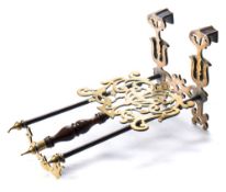 A 19th century brass fireside trivet: the shaped and pierced backplate with hooked finials,