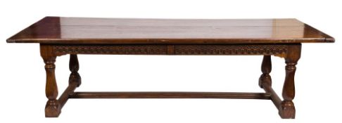 An oak dining table of large size and refectory type:, with an overhanging top and fluted frieze,