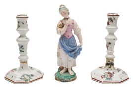 A Hochst [Damm] faience figure of a girl and a pair of Continental tin-glazed candlesticks: the