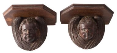 A pair of small carved oak wall brackets: with winged cherub supports, 18cm.