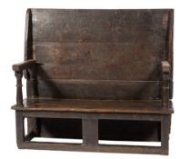 An 18th Century oak monks settle:, with a rectangular hinged top on turned uprights,