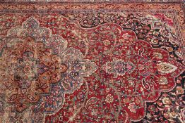 An Indo Persian carpet:, the wine cartouche field with a central pole medallion and all over floral,