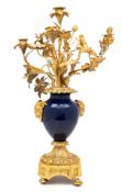 A late 19th century gilt metal and blue porcelain candelabrum: the ovoid-shaped vase with rams'