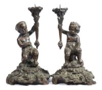 A pair of 19th century French bronze figural candlesticks: with seated putti holding pricket