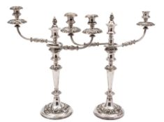 A pair of plated twin-branch candelabra: with urn-shaped nozzles on reeded and swept branches,