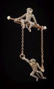 A bar brooch depicting two paste-set monkeys: with green cabochon eyes, one monkey seated,