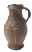 A German Medieval stoneware jug: of ribbed baluster form with strap handle and thumb moulded base,