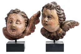 A pair of 17th century Italian carved wood and polychrome decorated winged cherub heads: mounted