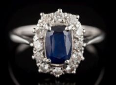 A sapphire and diamond oval cluster ring: the central oval sapphire approximately 7.6mm long x 5.