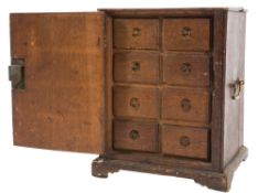 An 18th Century oak spice cabinet:, fitted with eight small drawers, enclosed by a panel door,