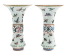 A matched pair of Chinese famille rose 'butterfly' beaker vases: each painted with numerous