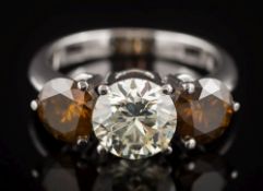 A diamond and cognac coloured diamond three-stone ring: the central round brilliant-cut diamond