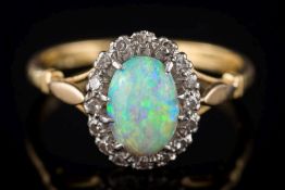 An opal and diamond oval cluster ring: the oval opal approximately 8.5mm long x 6.0mm wide x 2.