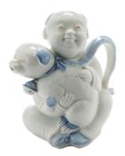 A Japanese Hirado blue and white teapot: in the form of a seated boy holding a puppy wearing a