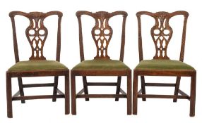 A set of four George III carved mahogany dining chairs in the Chippendale taste,