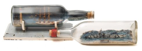 Two early 20th century ships in bottles:, one of a three masted ship off a lighthouse point,