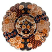 A Japanese Imari porcelain fluted charger: painted in underglaze blue and iron-red with flowers,