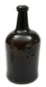 A sealed squat cylinder wine bottle: the dark olive/ brown body with pronounced kick up and short