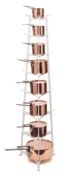 A set of eight graduated copper pans and covers: contained in a white painted wrought iron stand,