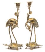 A pair of Chinese brass candlesticks: modelled in the form of cranes riding on the backs of turtles,