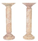 A matched pair of variegated cream and white marble cylindrical pedestals:, with pink,