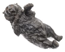 A Japanese bronze study of a bear: lying on its back with glass inset eyes and open mouth,