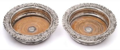 A pair of plated wine coasters: of circular form with scroll and foliate borders,