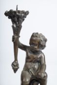 A pair of 19th century French bronze figural candlesticks: with seated putti holding pricket